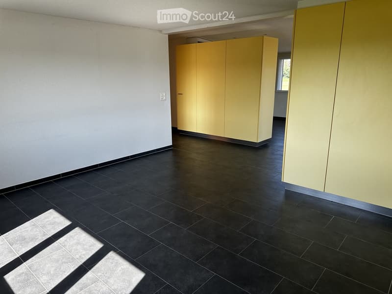 Empty room with black tiled floor and light yellow cabinets, no furniture or equipment present.