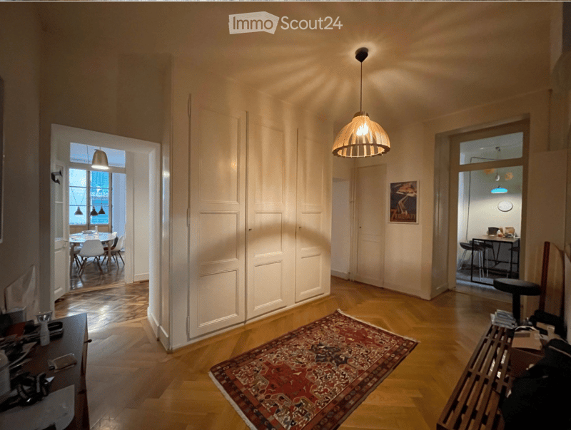 Bright hallway with wooden flooring, pendant light fixture, and open doors leading to adjacent rooms.