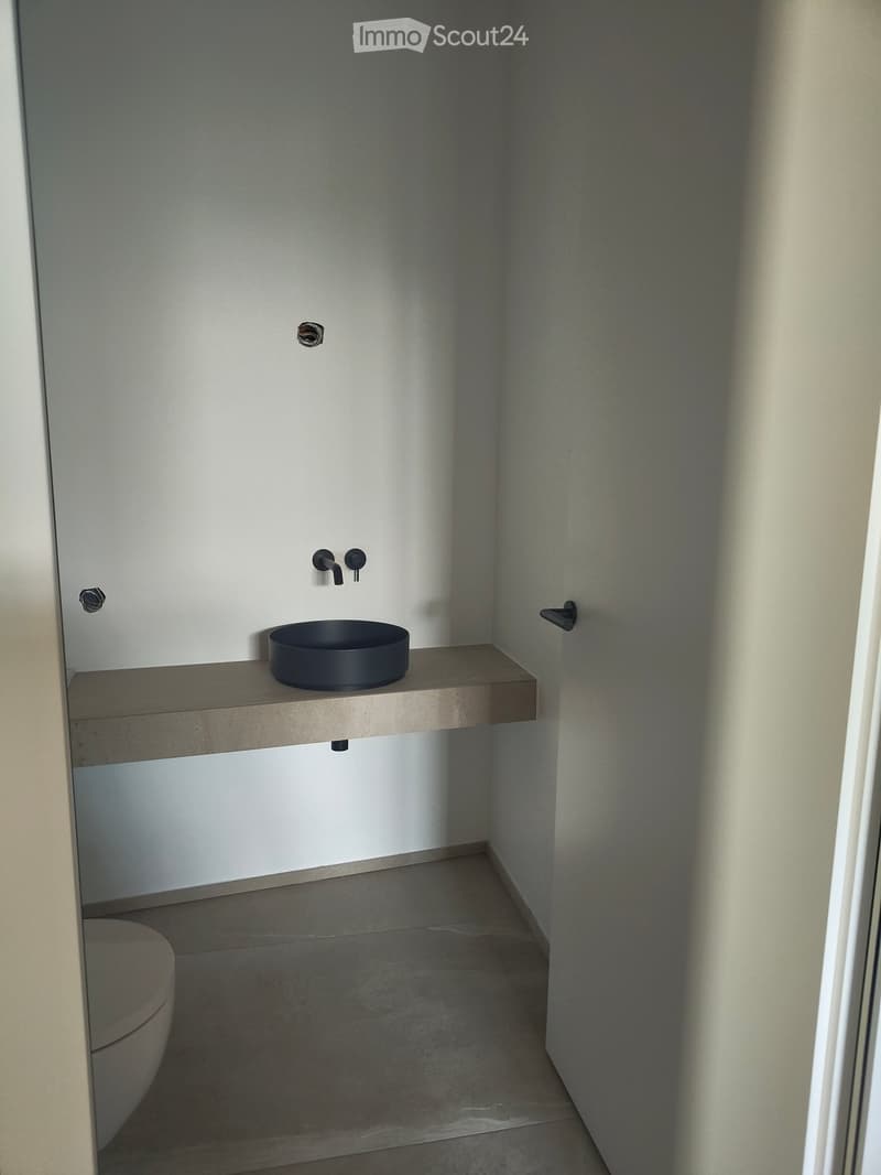 Minimalist bathroom with a toilet, a floating sink, and a modern faucet.