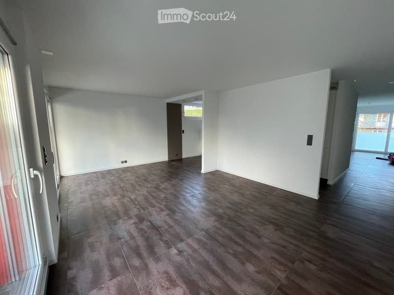 Empty room with wooden flooring, white walls, and large windows allowing natural light. No furniture or equipment present.