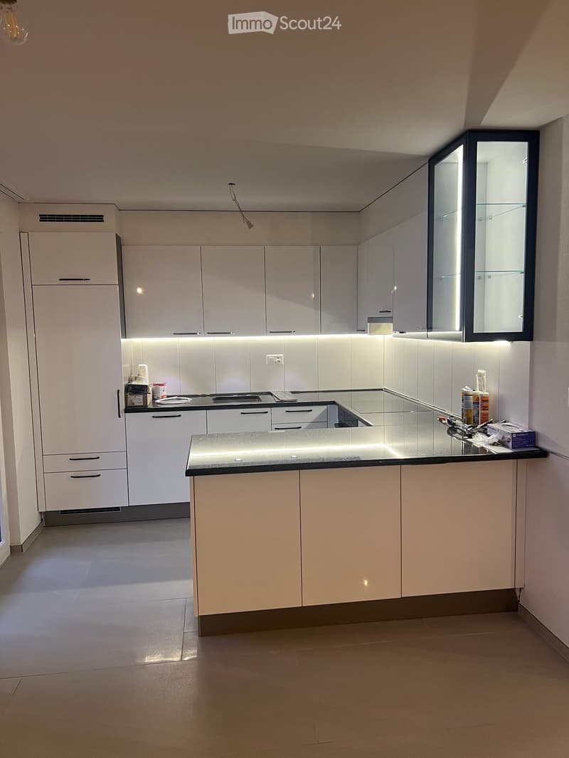 Modern kitchen with white cabinets, a central island, and a black countertop. The space features built-in appliances and sleek, contemporary design elements.