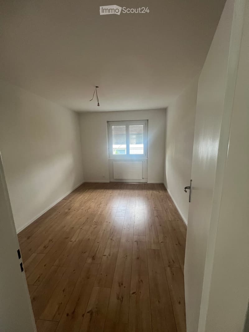 Empty room with wooden flooring, white walls, and a window with shutters. No furniture or equipment present.