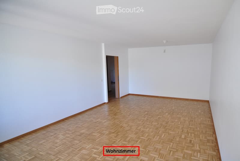 Empty room with light wooden flooring and white walls, featuring a single doorway leading to another space.