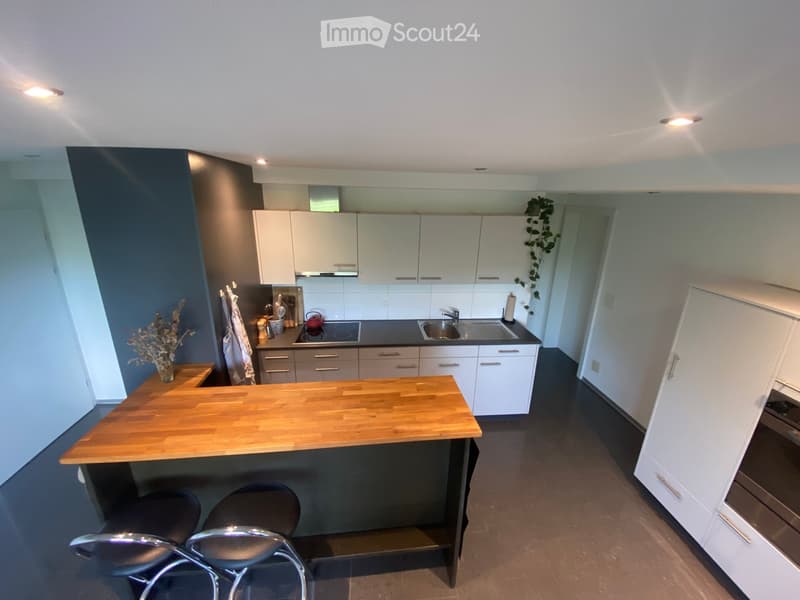 Modern kitchen with white cabinets, wooden countertop, stainless steel sink, and built-in appliances.