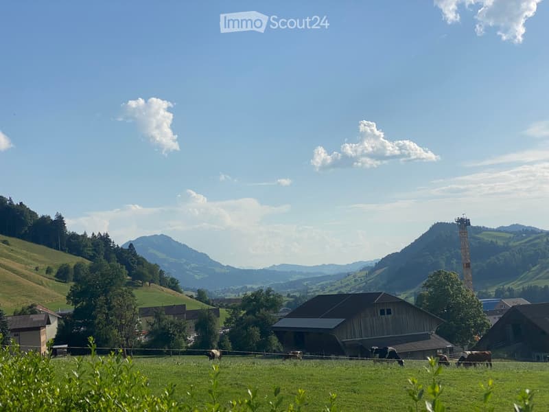 A scenic rural landscape with a barn, cows grazing in a field, and rolling hills under a clear blue sky.