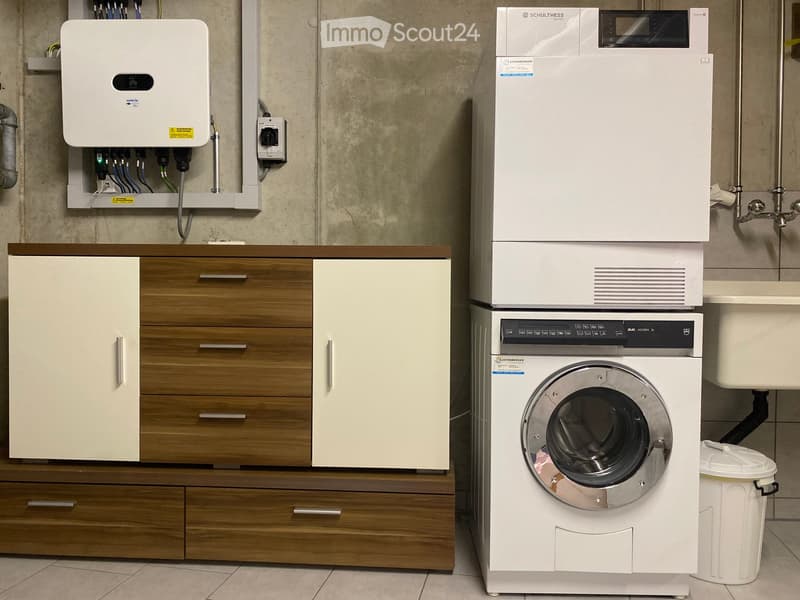 Bathroom with a washing machine, wooden cabinet, and drawers.