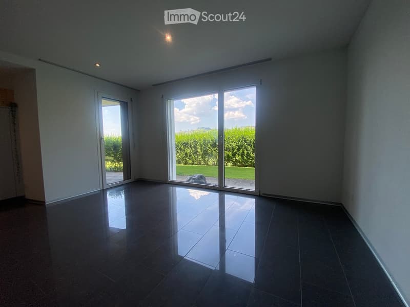 Empty room with dark tiled flooring, white walls, and large sliding glass doors leading to an outdoor area.