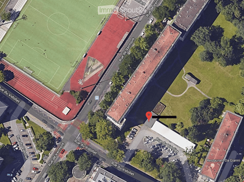 Aerial view of a sports complex with a football field, running track, and surrounding buildings and roads.