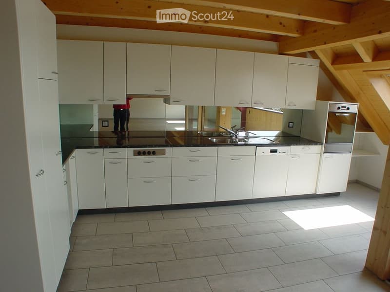 Modern kitchen with white cabinets, stainless steel appliances, and a black countertop.
