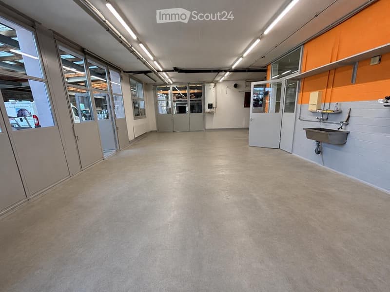 Empty room with grey carpeted floor, white walls, large windows, and a sink on the right side.
