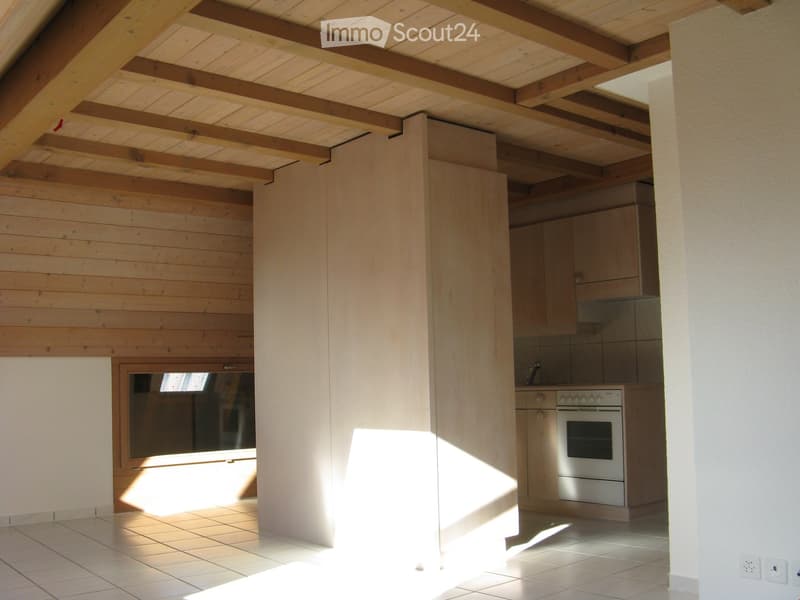 Bright kitchen with wooden beams, tiled floor, and modern oven. Natural light streams in from a window.