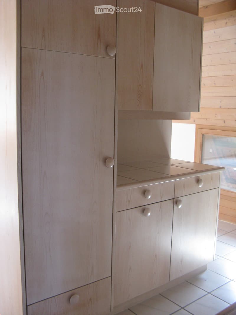 Light wood kitchen cabinet with multiple drawers and doors, featuring round knobs.