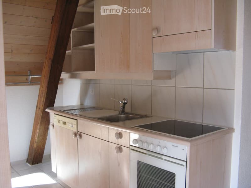 Modern kitchen with light wood cabinets, stainless steel sink, electric stove, oven, and dishwasher.