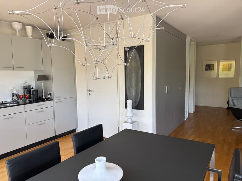 Modern kitchen and dining area with white cabinets, black dining table, chairs, and decorative vases.