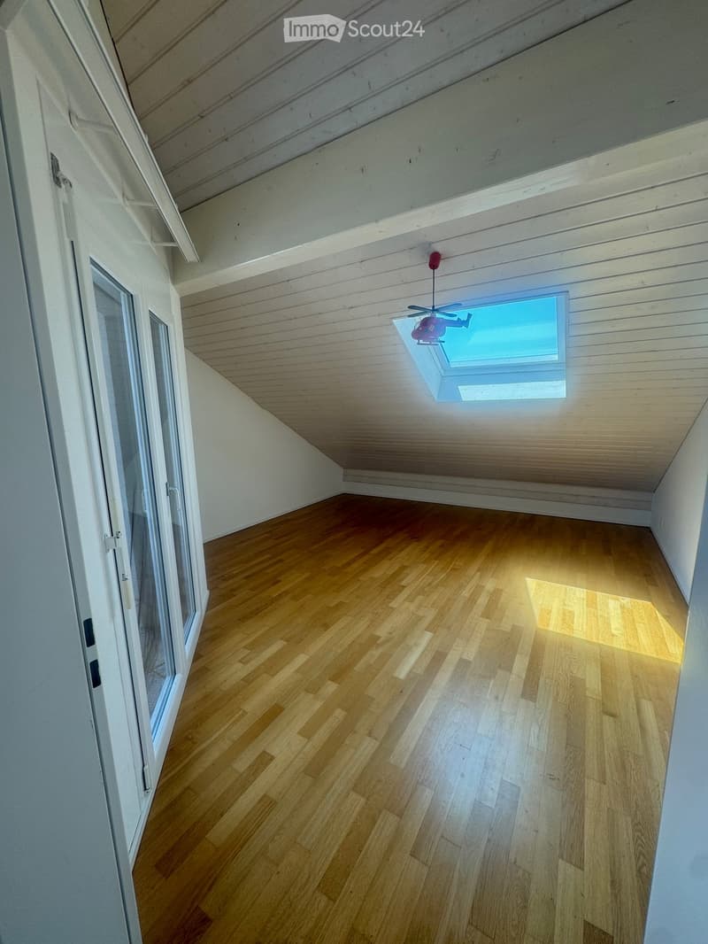 Empty room with wooden flooring, white walls, and a skylight window in the ceiling.