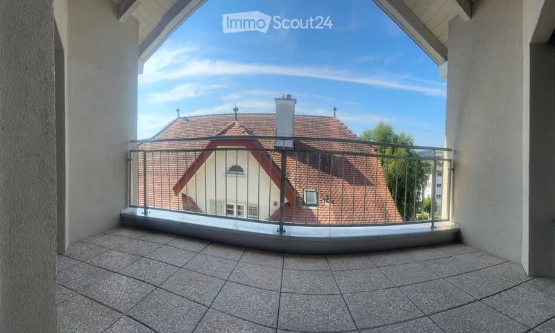 Balcony with tiled floor, metal railing, and view of a house with a red-tiled roof and chimney.