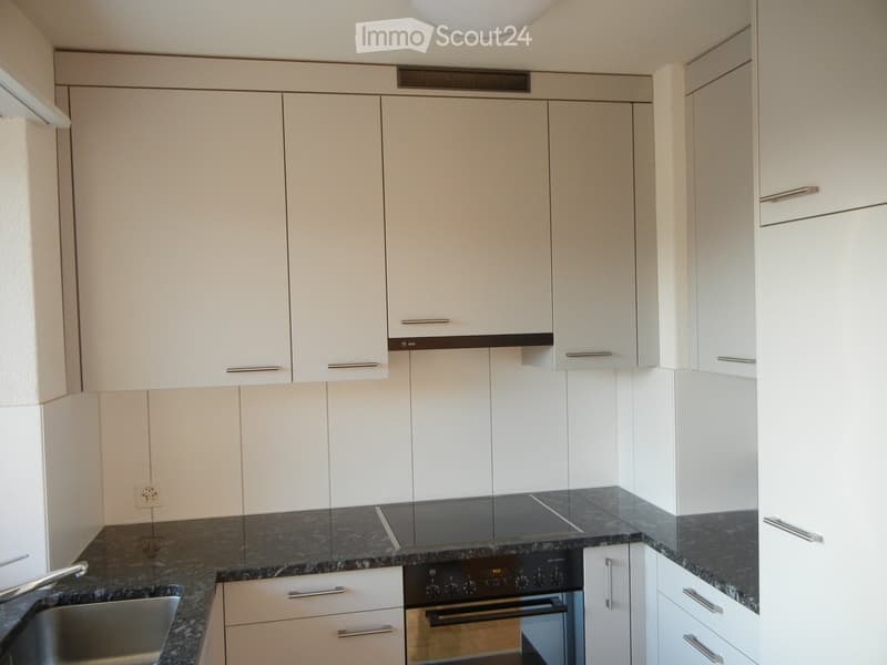 Modern kitchen with white cabinets, granite countertops, and stainless steel appliances including a sink and oven.