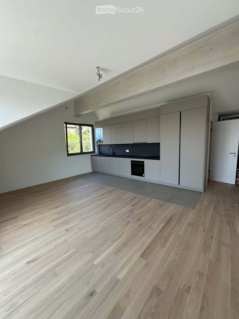Modern kitchen with light wood flooring, white cabinets, and a black countertop. Features a sink, faucet, and built-in oven.