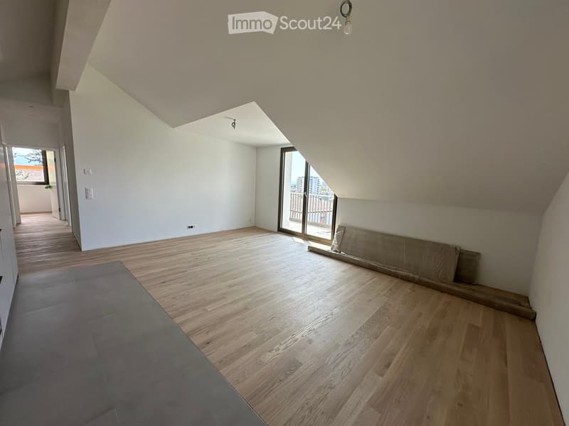 Empty room with wooden flooring, white walls, and a large window leading to a balcony.