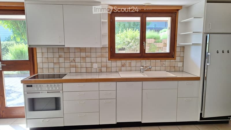 Modern kitchen with white cabinets, wooden countertops, and stainless steel appliances including an oven, refrigerator, and sink.