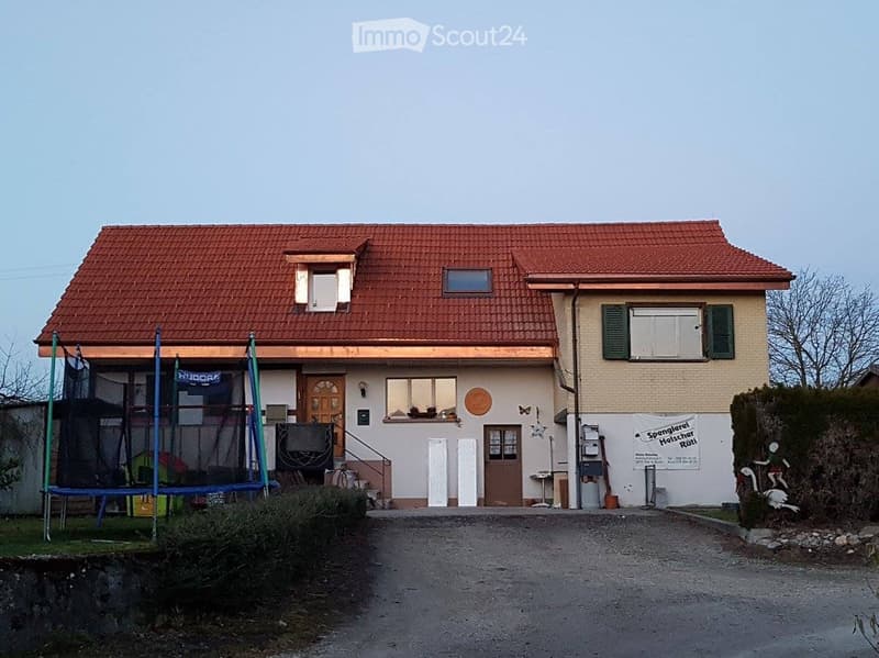 2 story house, red roof, white windows, wooden doors, driveway, trampoline, front door, signboard, shrubs
