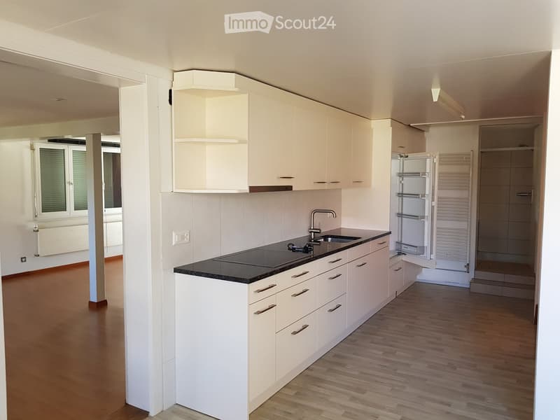 Open kitchen with modern appliances, white cupboards, black granite countertops, wooden flooring, gas stove, sink, refrigerator, ample natural light from nearby windows.