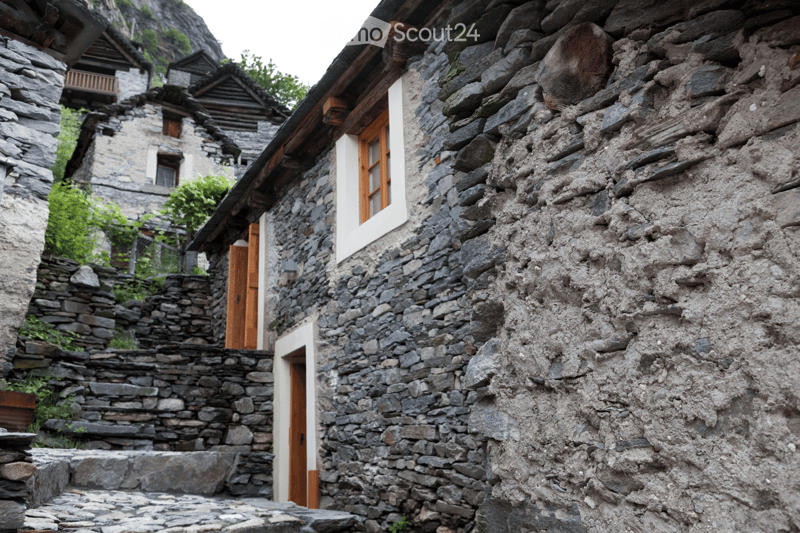 Stone building with wooden doors and windows, rustic stone walls, and a narrow pathway leading to the entrance.