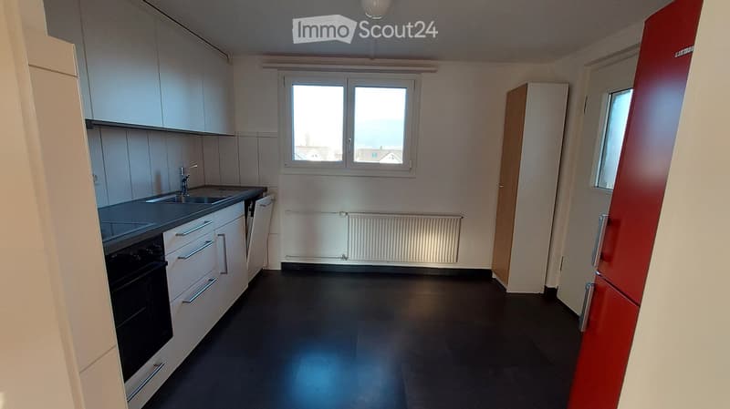Modern kitchen with white cabinets, black countertops, and a dark floor. Features a sink with a faucet, an oven, and a radiator under the window.