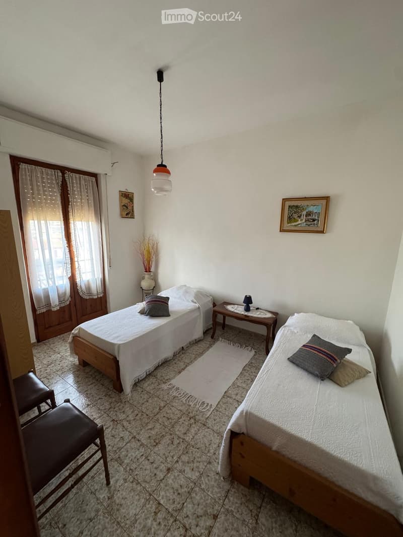 Cozy bedroom with two single beds, nightstand, small table, and decorative items.