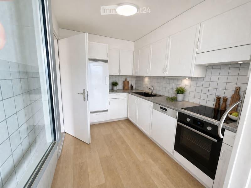 Modern kitchen with white cabinets, wooden flooring, stainless steel appliances, and a granite countertop.