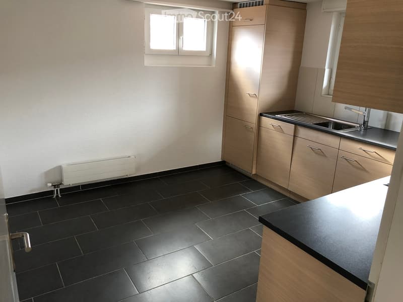 modern kitchen with cabinets, countertop, sink, faucet, small window, radiator, black tiled floor