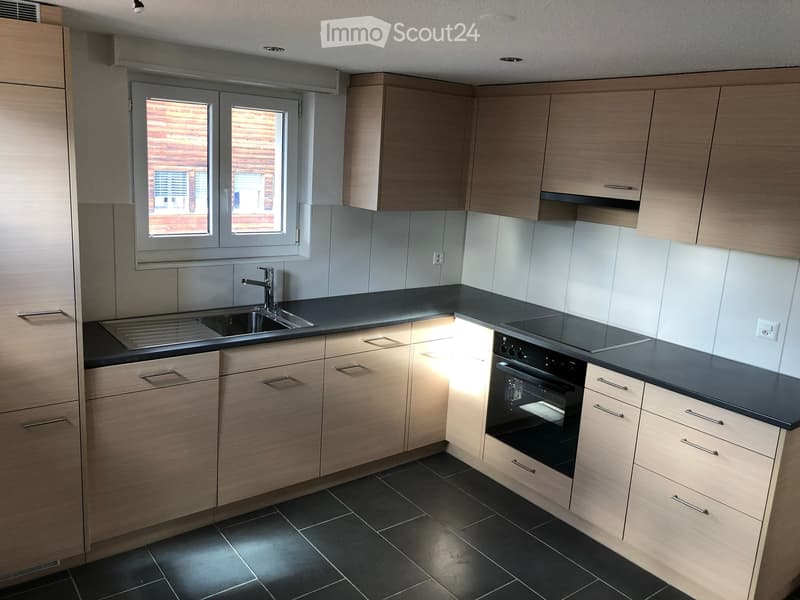 modern kitchen, wooden cabinets, black countertops, stainless steel sink, gas stove, oven, black tiled floor, window