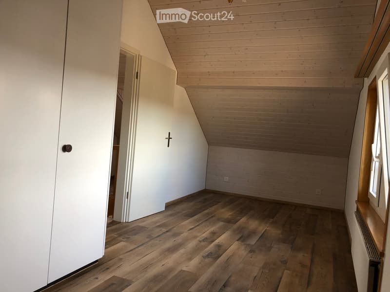 empty room with wooden floor, white walls, wooden ceiling, window, doorway