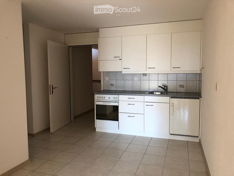 Modern kitchen with white cabinets, tiled backsplash, and granite countertop. Features an oven, sink, and faucet.