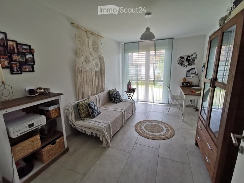 A cozy living room with a sofa, small table, chair, cabinet, mirror, and decorative items.