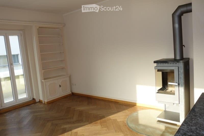Empty room with wooden floor, glass door, fireplace, white walls, shelves, and power outlet