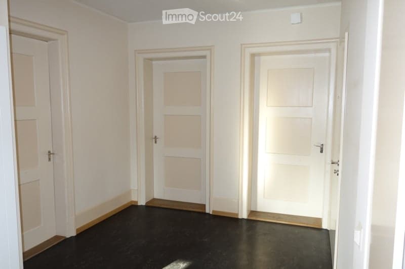 White walls, black floor, two closed doors, one open door.