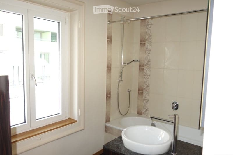 Bathroom with a window, bathtub, sink, and shower.