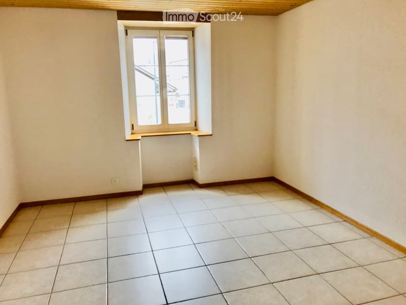 Empty room with tiled floor, white walls, and a window with double doors leading to a balcony.