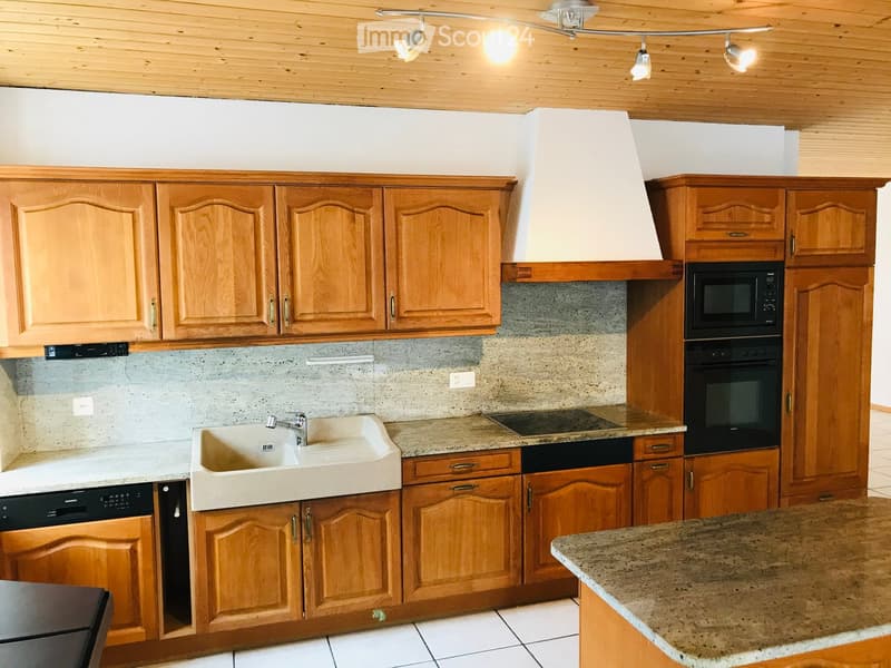 Modern kitchen with wooden cabinets, granite countertops, stainless steel appliances, and a white sink.