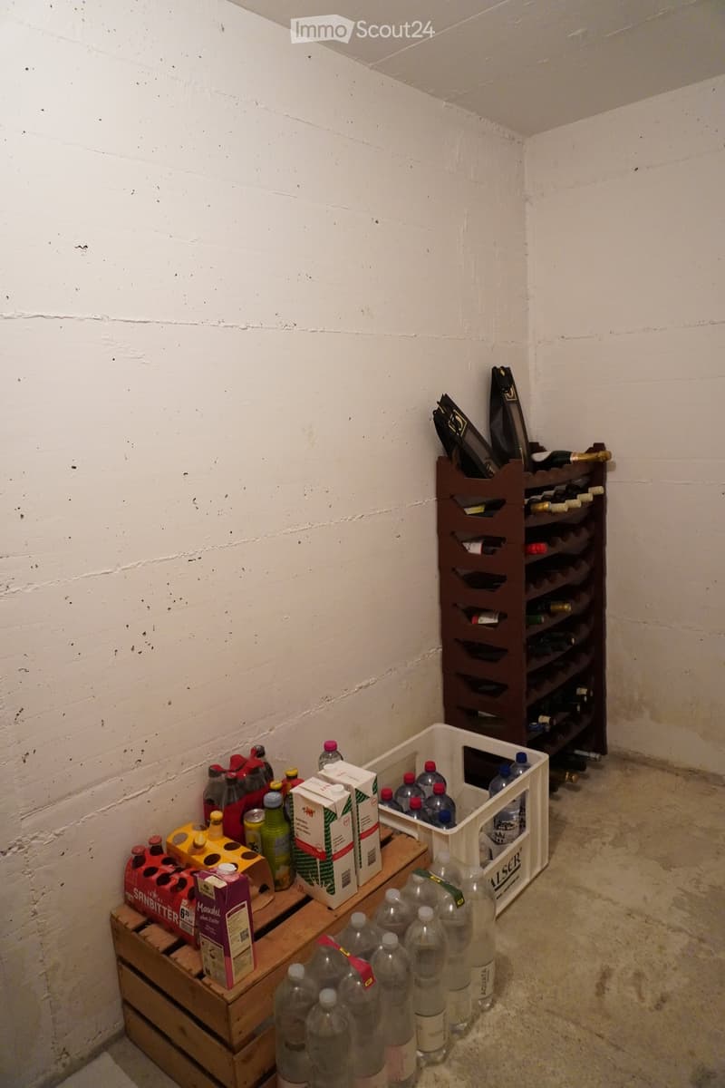 A small storage room with a wine rack, plastic crate, wooden crate, and various bottles and milk cartons.