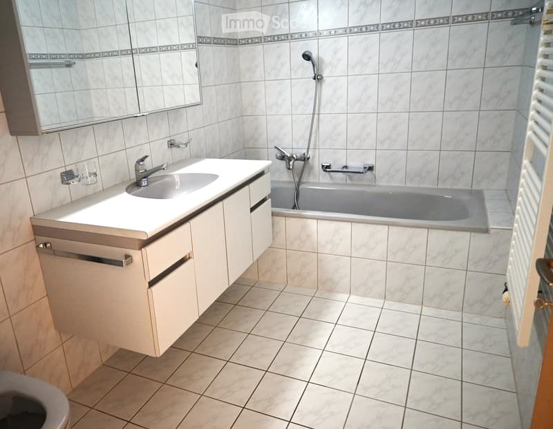 Bathroom with white tiles, bathtub, sink, mirror, and toilet