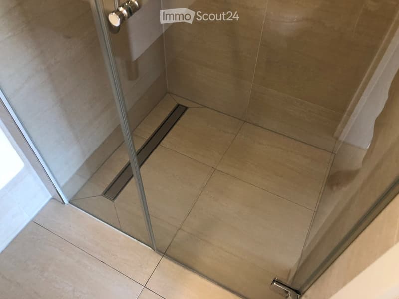 Glass shower door, tiled floor, drain in the floor