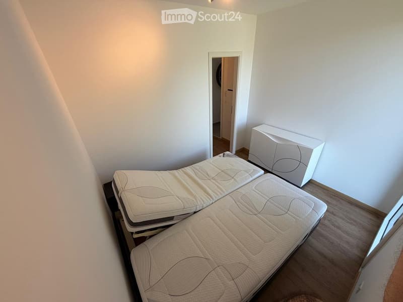 Bedroom with a large bed, nightstand, and a partially visible adjacent room.