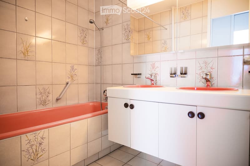 Bathroom with a bathtub, double sink, and a shower head.