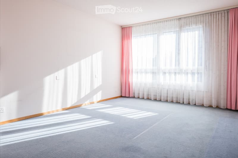 empty room, white walls, carpeted floor, large window with pink curtains, power outlets