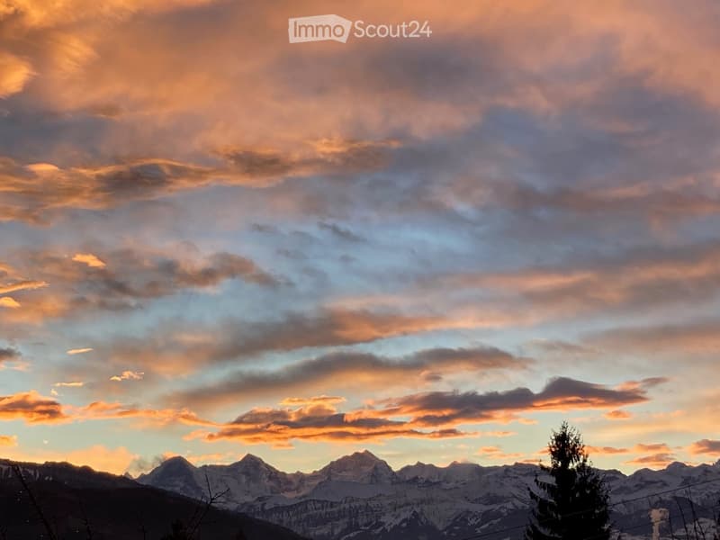 A scenic mountain view with snow-capped peaks under a colorful sunset sky.