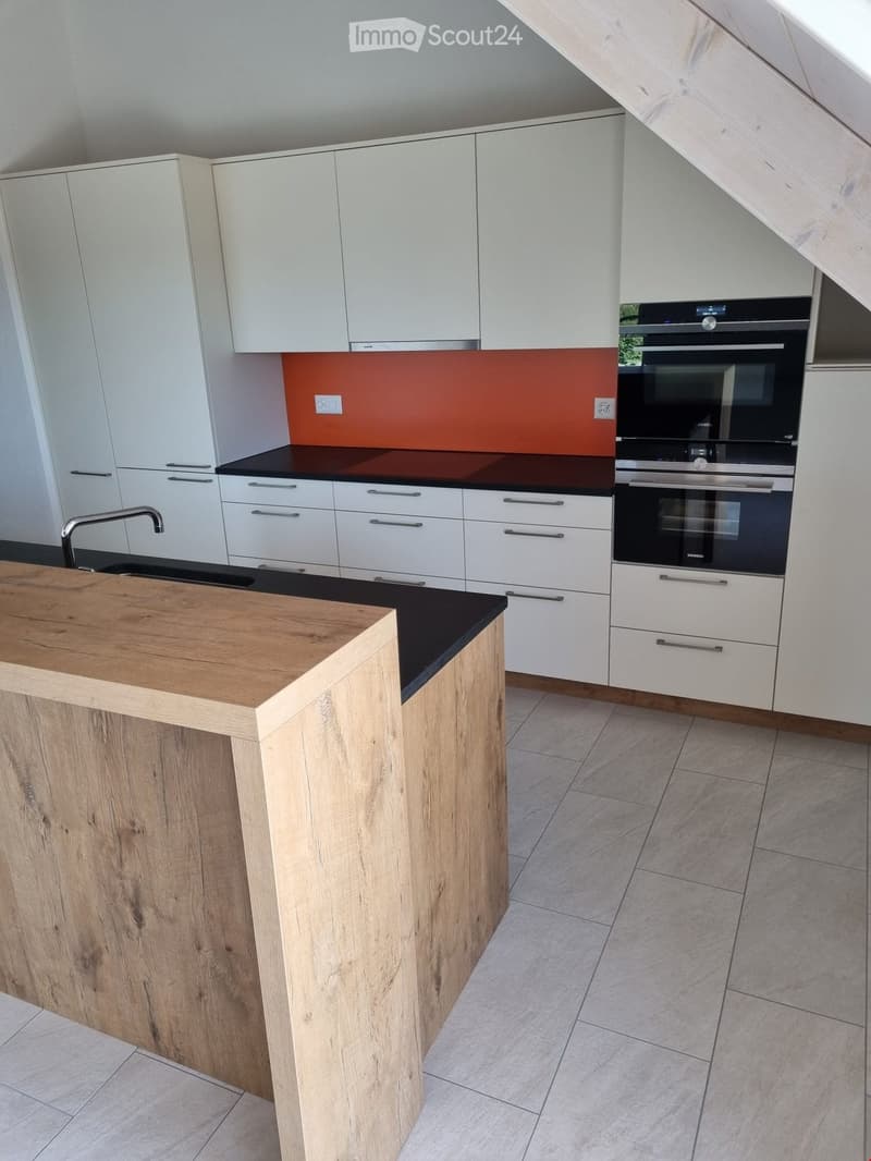 Modern kitchen with white cabinets, a wooden island, and a black countertop. Features include a stainless steel oven, a sink with a modern faucet, and a sleek design.