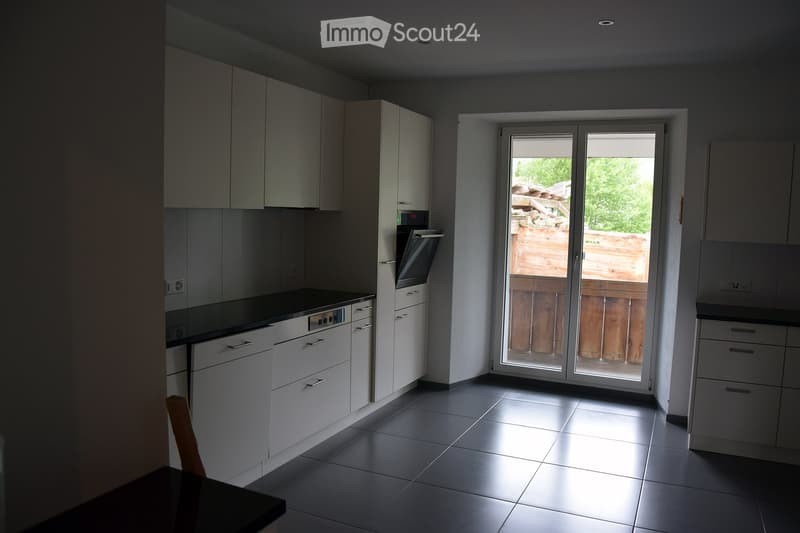 Modern kitchen with white cabinets, dark countertops, and a sliding glass door leading to an outdoor area.