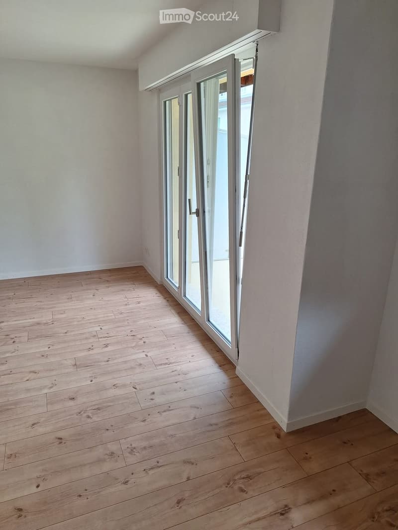 Empty room with wooden flooring and large glass sliding doors leading to a balcony.